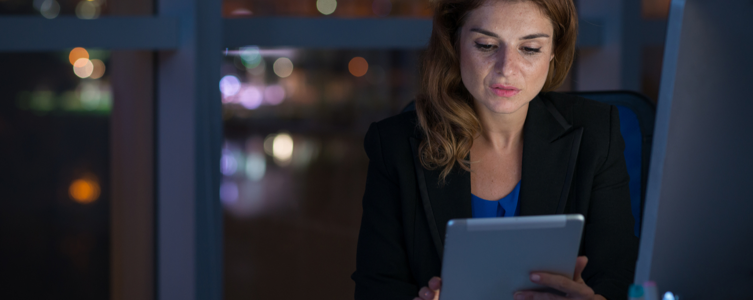 Female professional working on digital tablet in night office